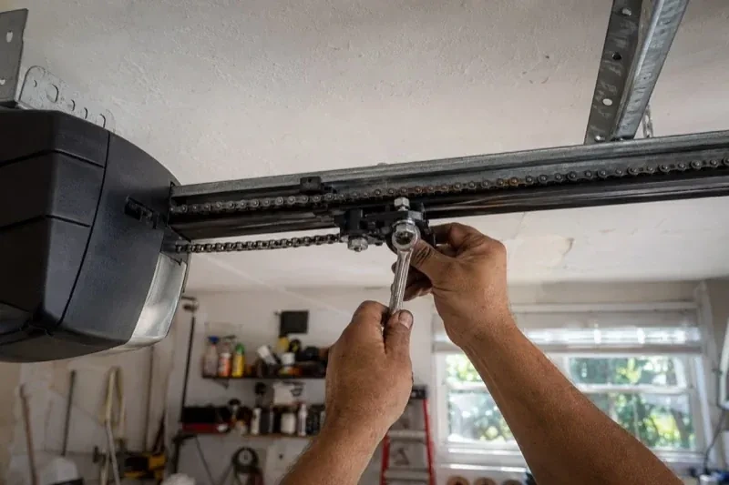 Hands holding a wrench against an opener trolley beneath a chain rail — Chain-Drive Opener Repair, Springwater