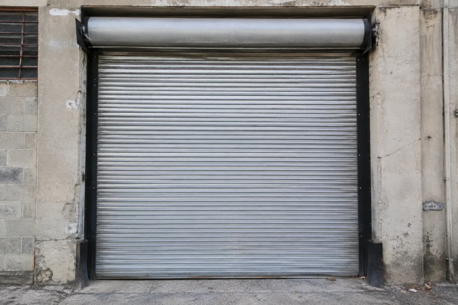 Closed metal rolling shutter in a weathered warehouse opening. — Commercial Rolling Door Repair, Springwater