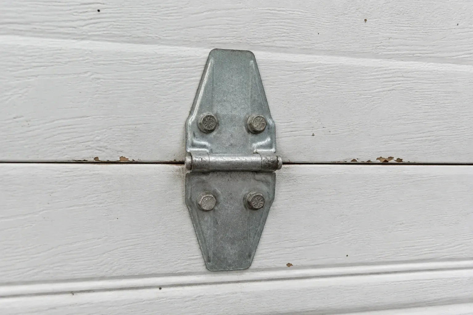 Metal center hinge across a seam in a white sectional garage door. — Garage Door Hinge Replacement, Springwater